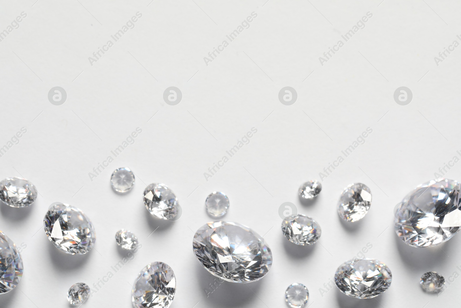 Photo of Many beautiful shiny diamonds on white background, flat lay. Space for text