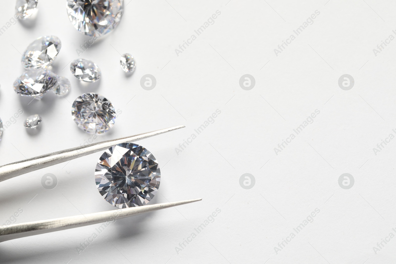 Photo of Many beautiful shiny diamonds and tweezers on white background. Space for text