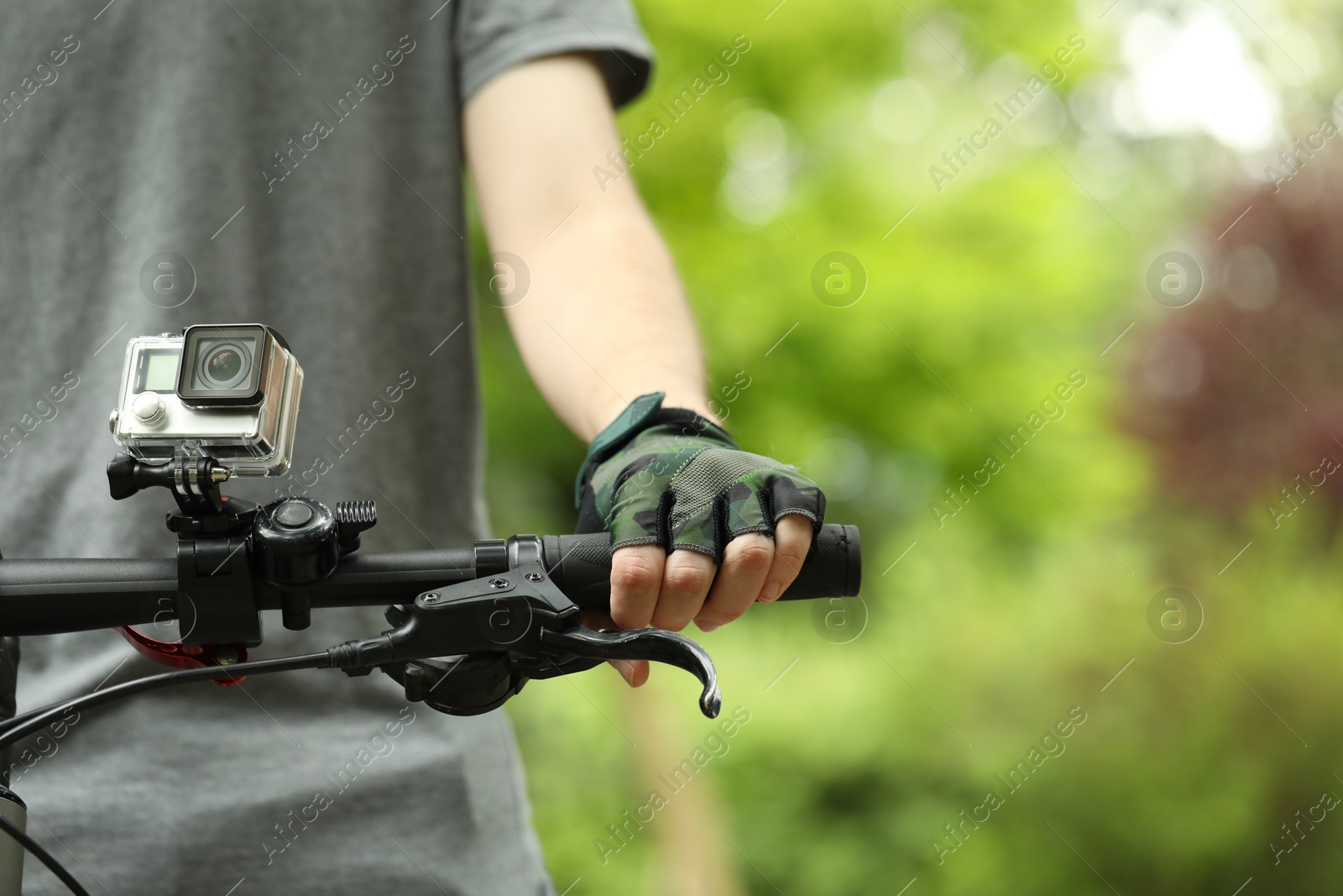 Photo of Man riding bicycle with modern action camera outdoors, closeup. Space for text