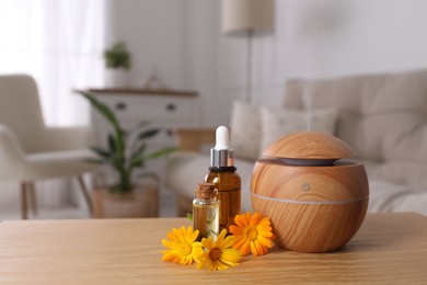 Photo of Essential oil diffuser, cosmetic products and calendula flowers on wooden table at home, space for text