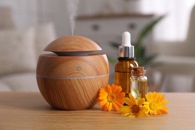 Essential oil diffuser, cosmetic products and calendula flowers on wooden table at home