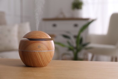 Photo of Essential oil diffuser on wooden table at home, space for text