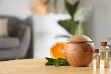 Photo of Essential oil diffuser, cosmetic products, mint and orange on wooden table at home, space for text