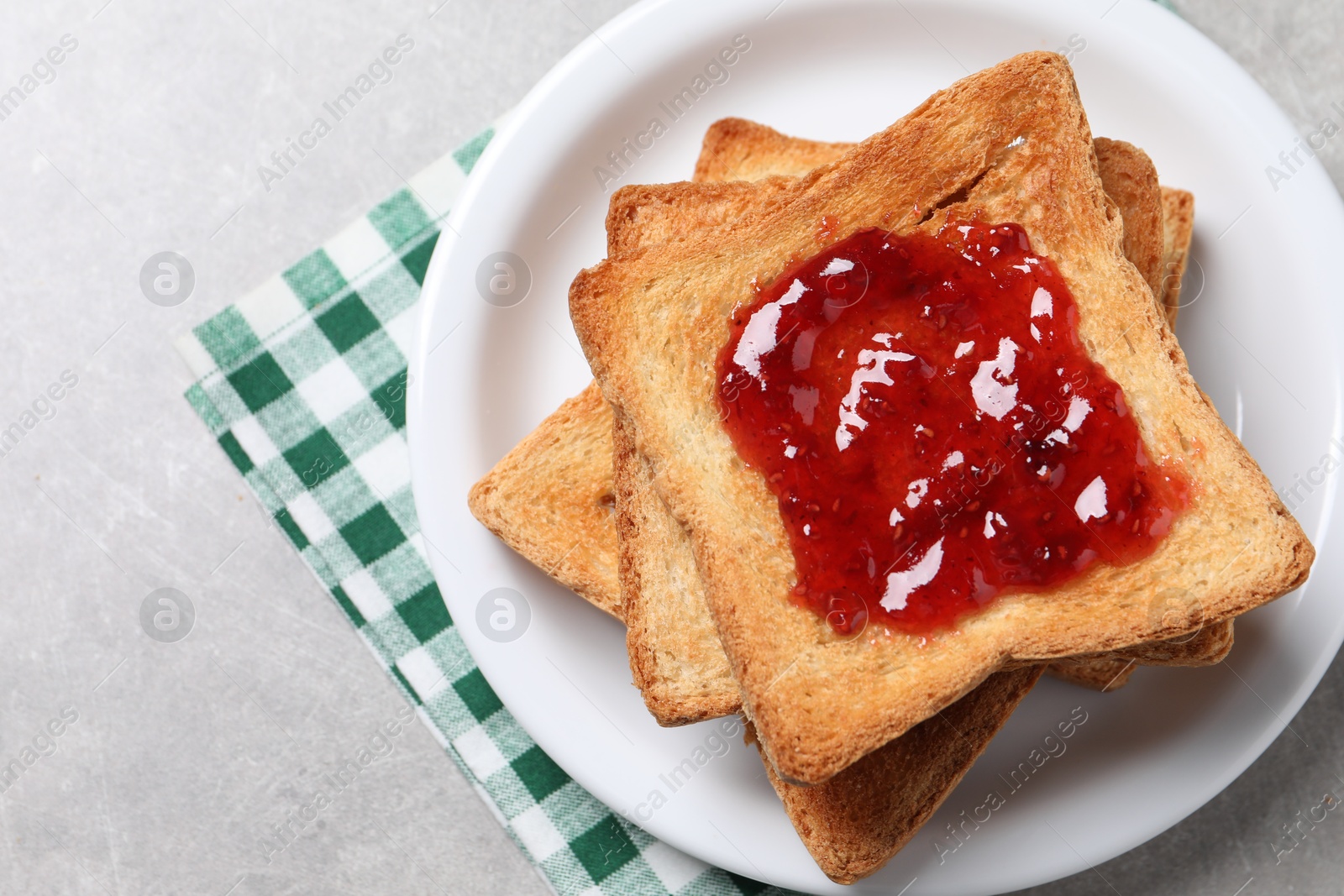 Photo of Delicious toasts with jam on light table, top view