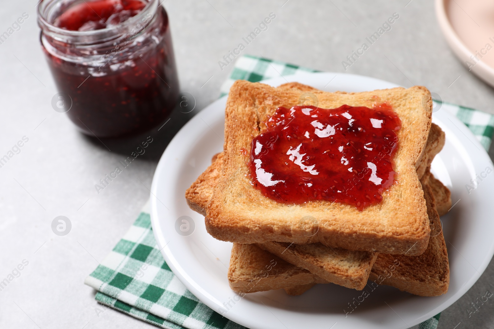 Photo of Delicious toasts with jam on light table, closeup