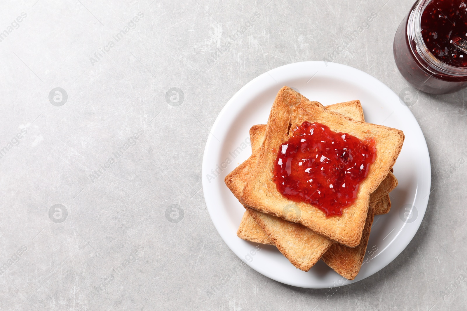 Photo of Delicious toasts with jam on light table, top view. Space for text