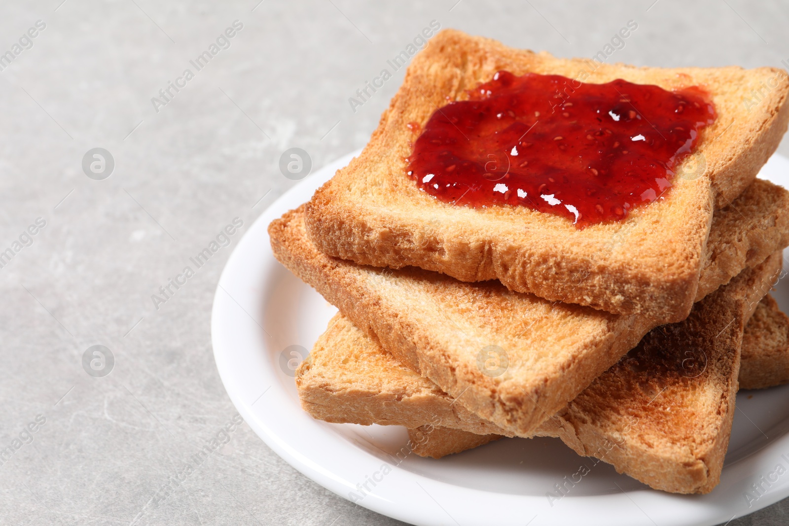 Photo of Delicious toasts with jam on light table, closeup