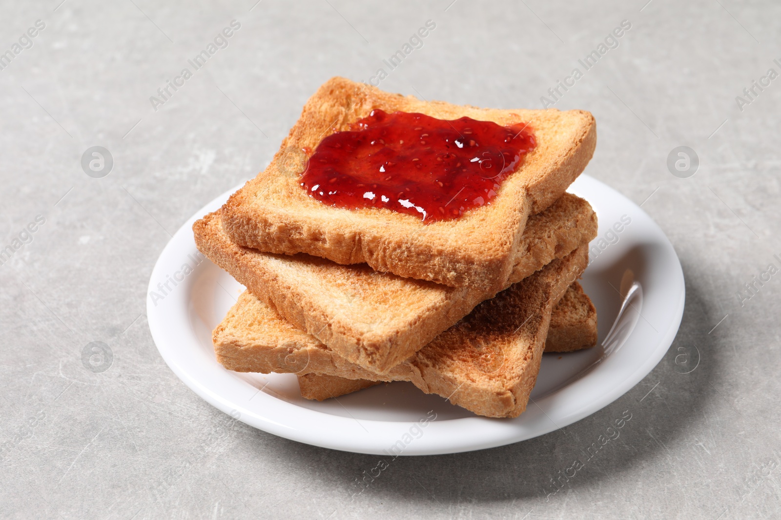 Photo of Delicious toasts with jam on light table, closeup