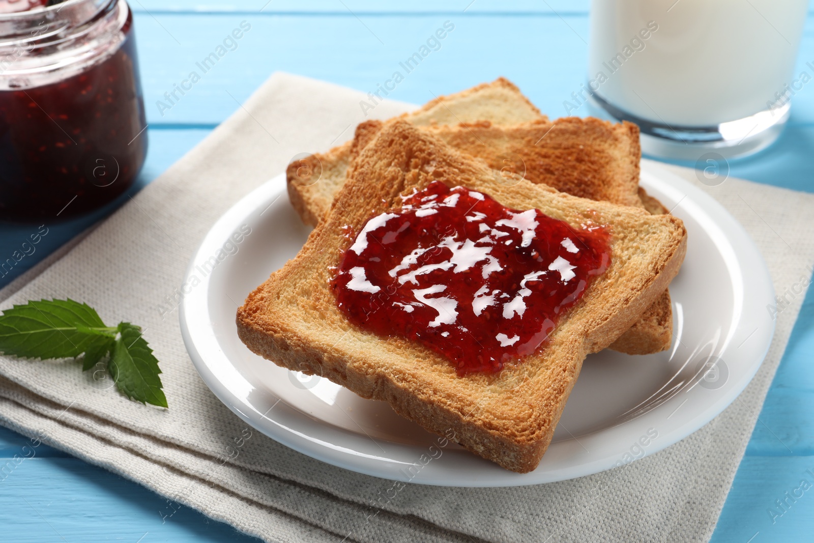 Photo of Delicious toasts with jam on light blue wooden table, closeup