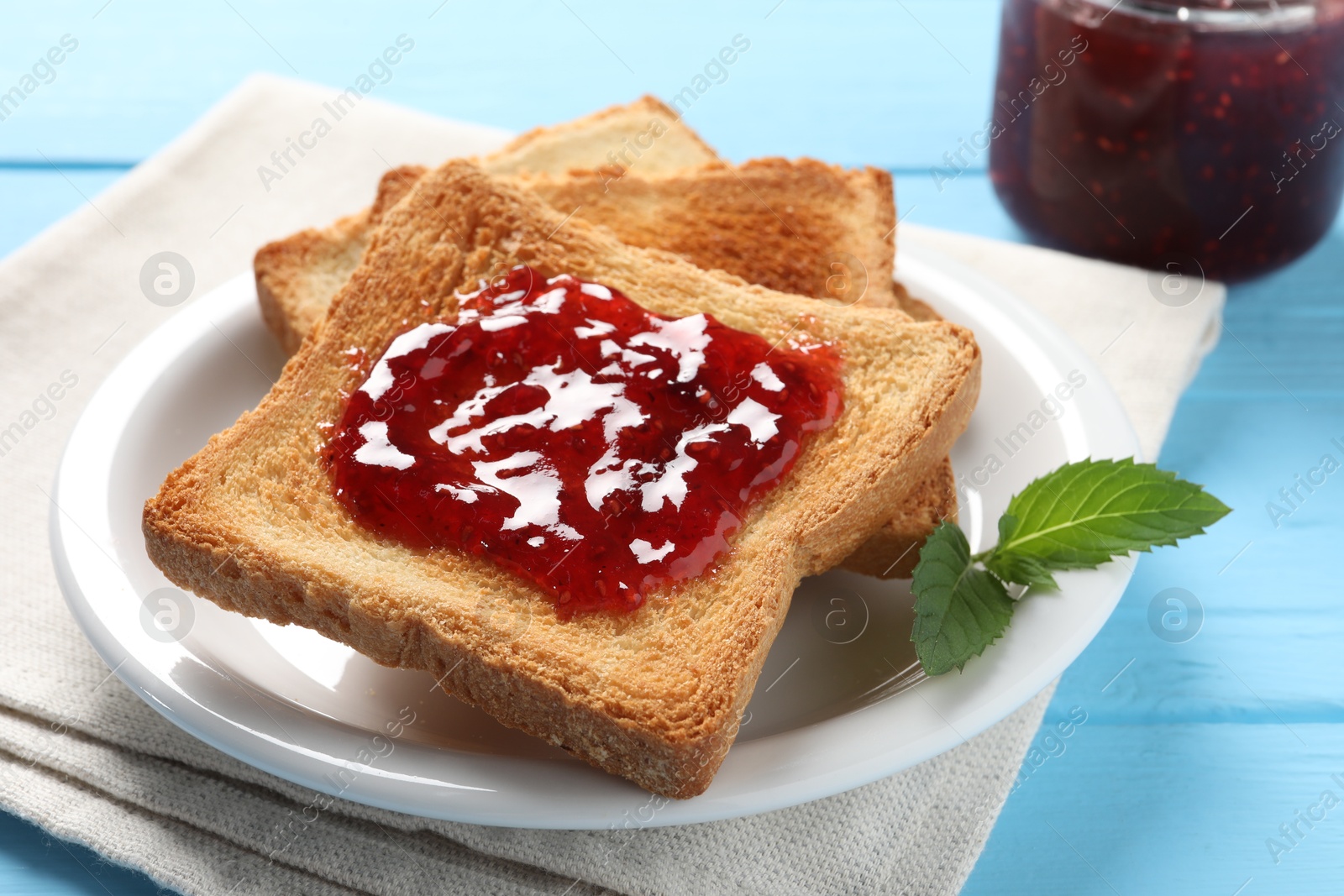 Photo of Delicious toasts with jam on light blue wooden table, closeup