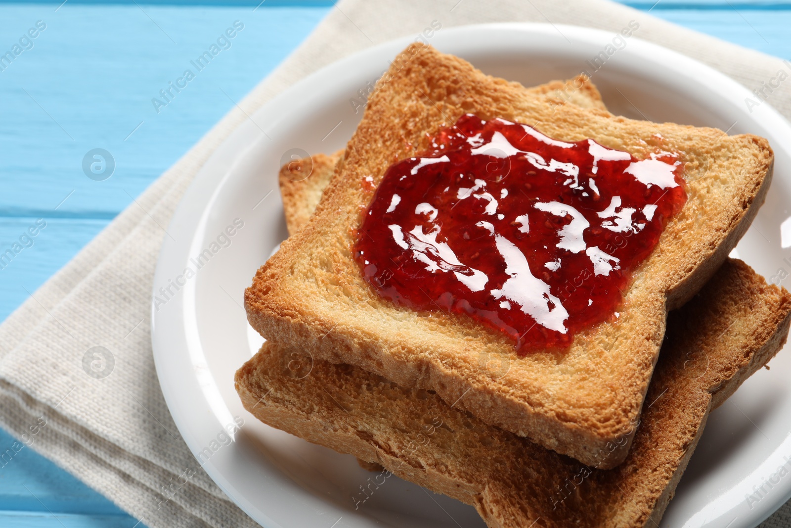 Photo of Delicious toasts with jam on light blue wooden table, closeup