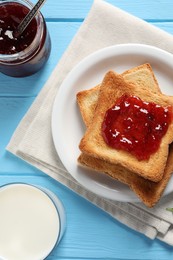 Delicious toasts with jam and milk on light blue wooden table, flat lay