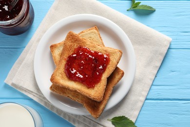 Delicious toasts with jam and milk on light blue wooden table, flat lay