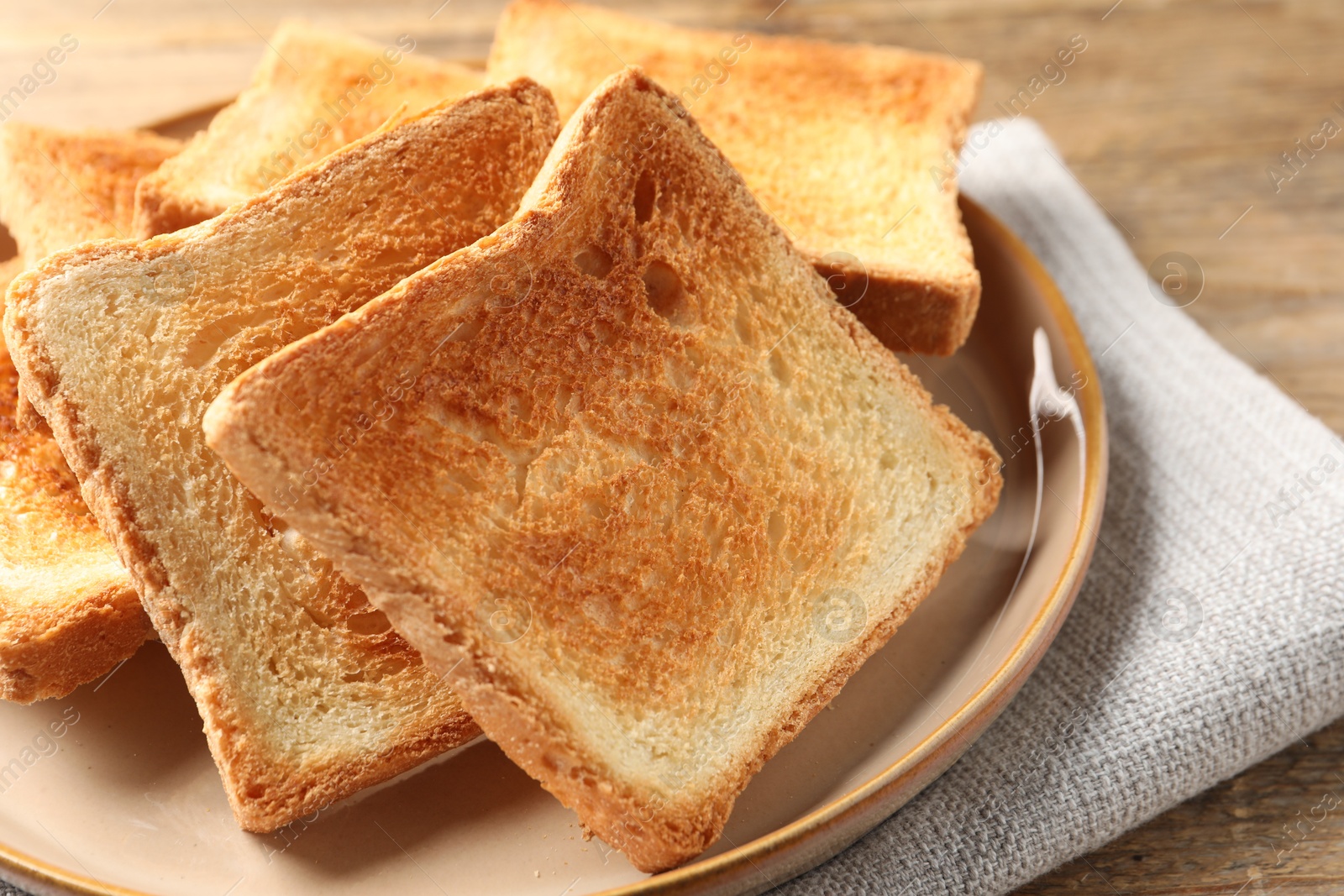 Photo of Slices of delicious toasted bread on wooden table, closeup