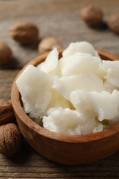 Photo of Natural shea butter and nuts on wooden table, closeup