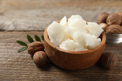 Photo of Natural shea butter and nuts on wooden table, closeup