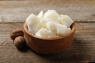 Photo of Natural shea butter and nuts on wooden table, closeup