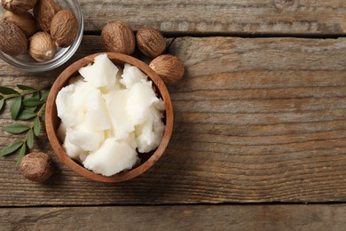 Natural shea butter and nuts on wooden table, flat lay. Space for text