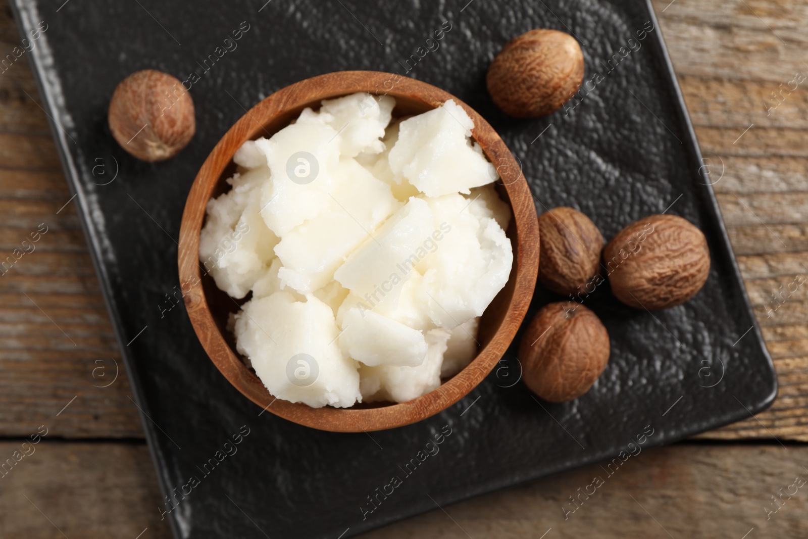 Photo of Natural shea butter and nuts on wooden table, top view