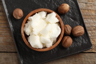 Natural shea butter and nuts on wooden table, top view