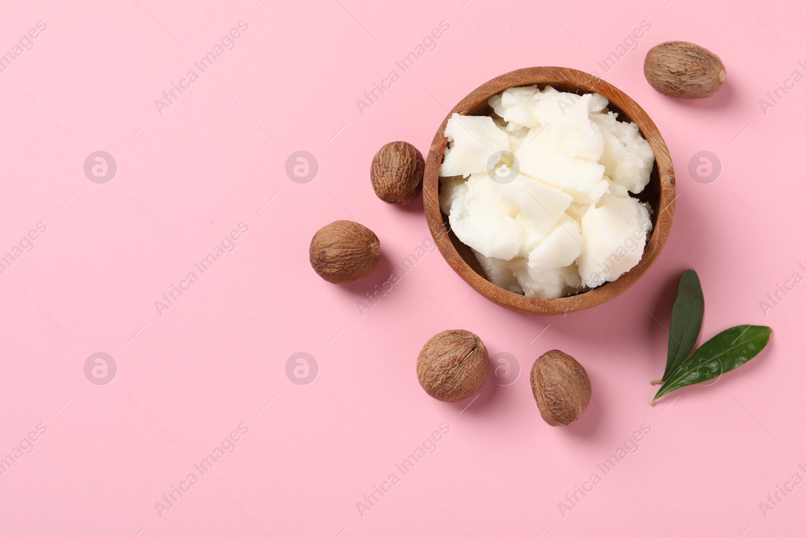 Photo of Natural shea butter and nuts on pink background, flat lay. Space for text