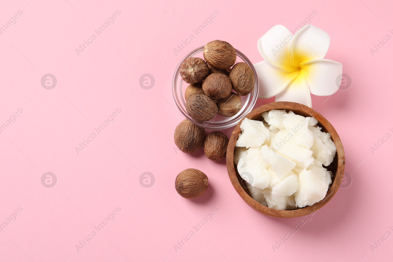 Photo of Natural shea butter, nuts and plumeria flower on pink background, flat lay. Space for text