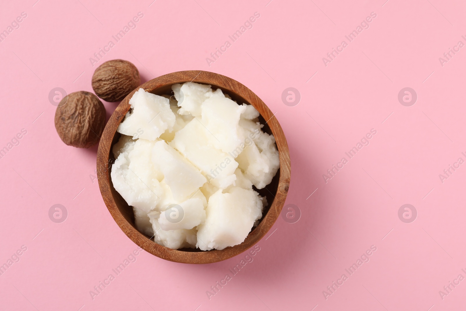 Photo of Natural shea butter and nuts on pink background, top view. Space for text