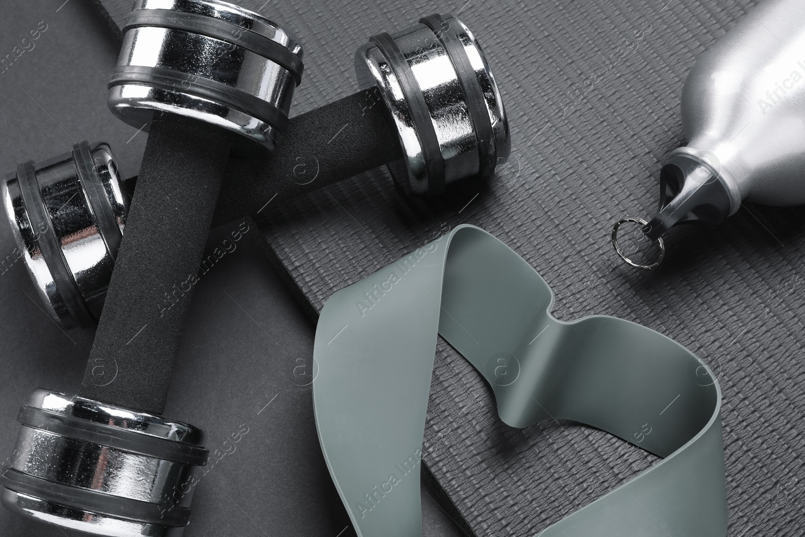 Photo of Dumbbells, yoga mat, thermo bottle and fitness elastic band on black background, above view