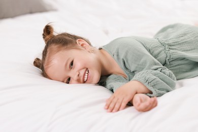 Portrait of happy little girl on bed