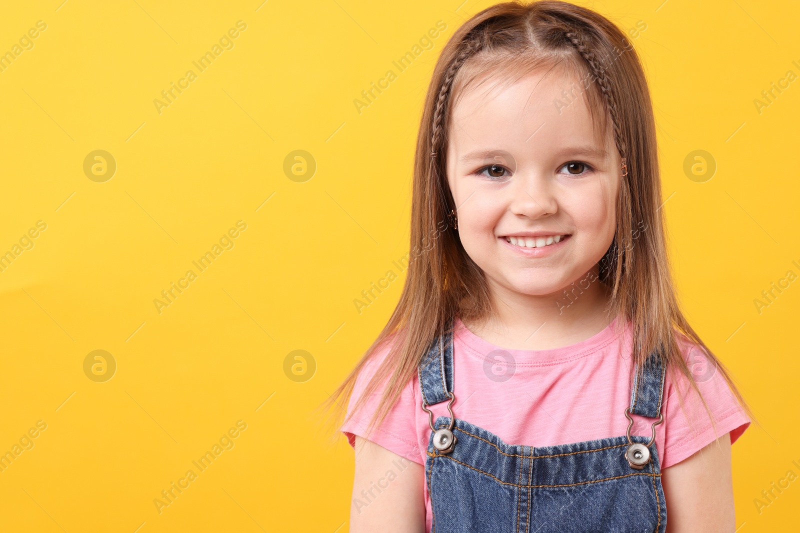 Photo of Portrait of happy little girl on orange background, space for text