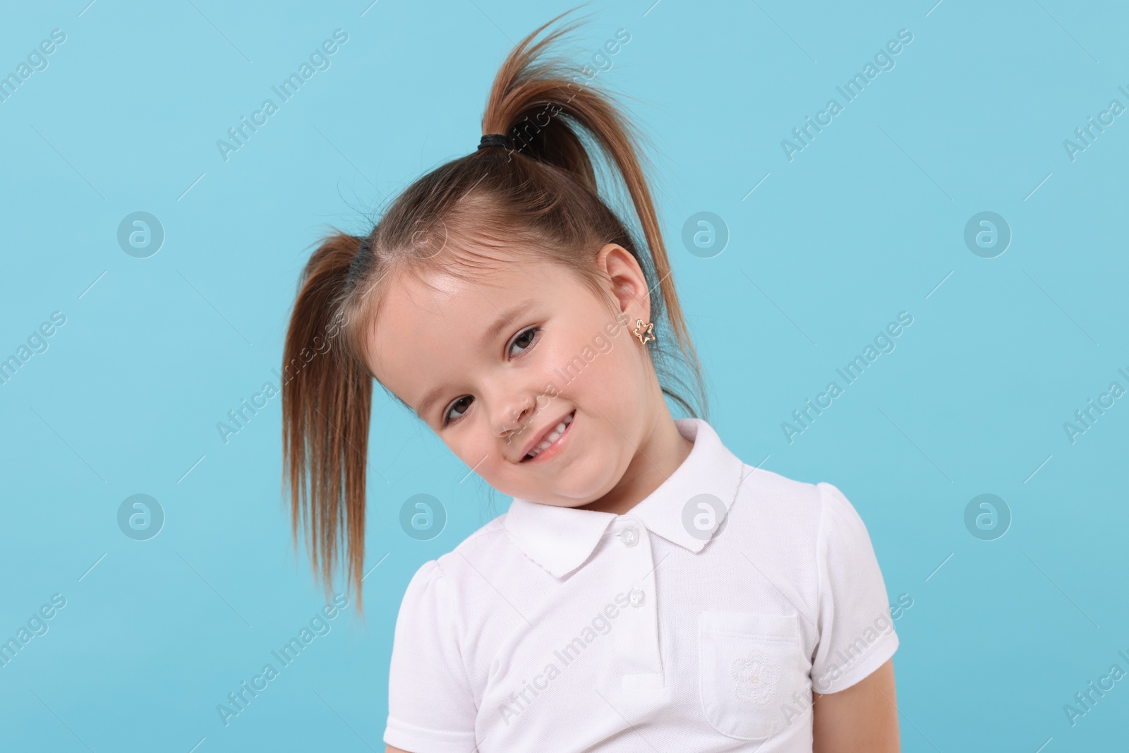 Photo of Portrait of cute little girl on light blue background