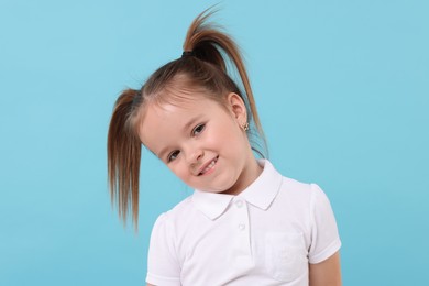 Portrait of cute little girl on light blue background