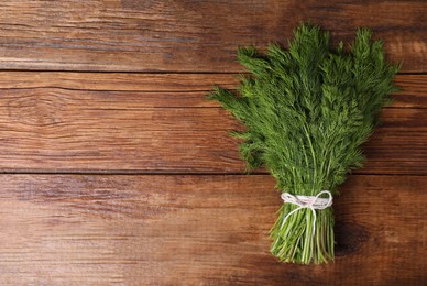 Photo of Bunch of fresh green dill on wooden table, top view. Space for text