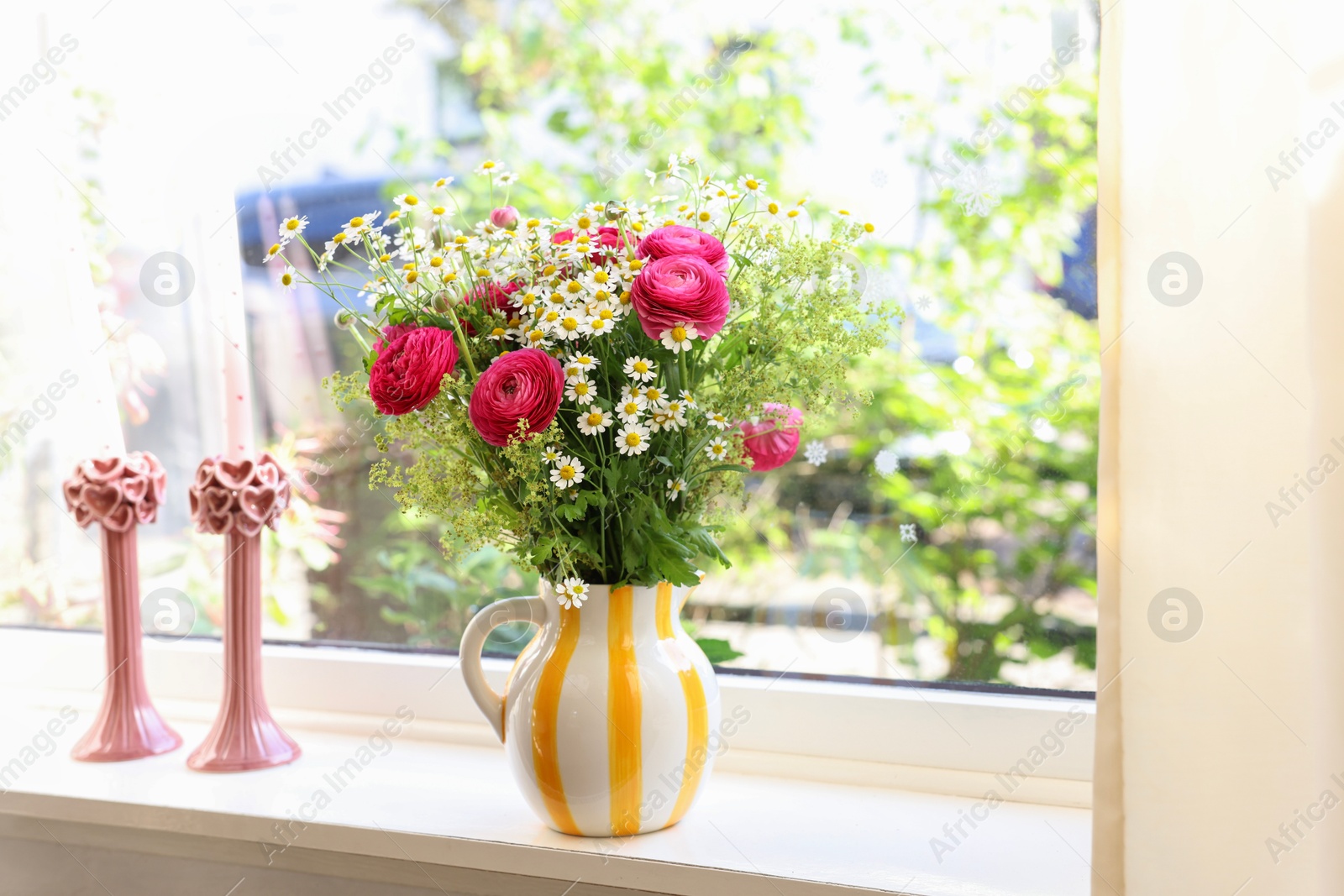 Photo of Beautiful ranunculus flowers and chamomiles in vase on windowsill indoors