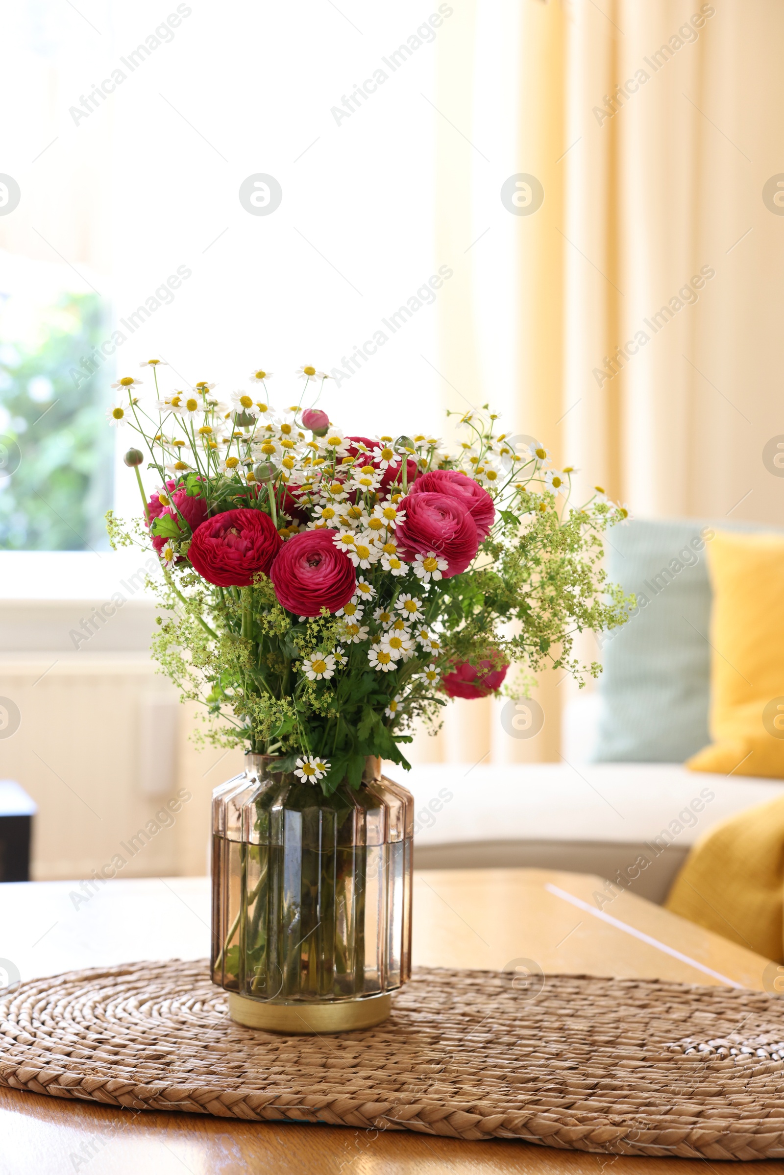 Photo of Beautiful ranunculus flowers and chamomiles in vase on table indoors