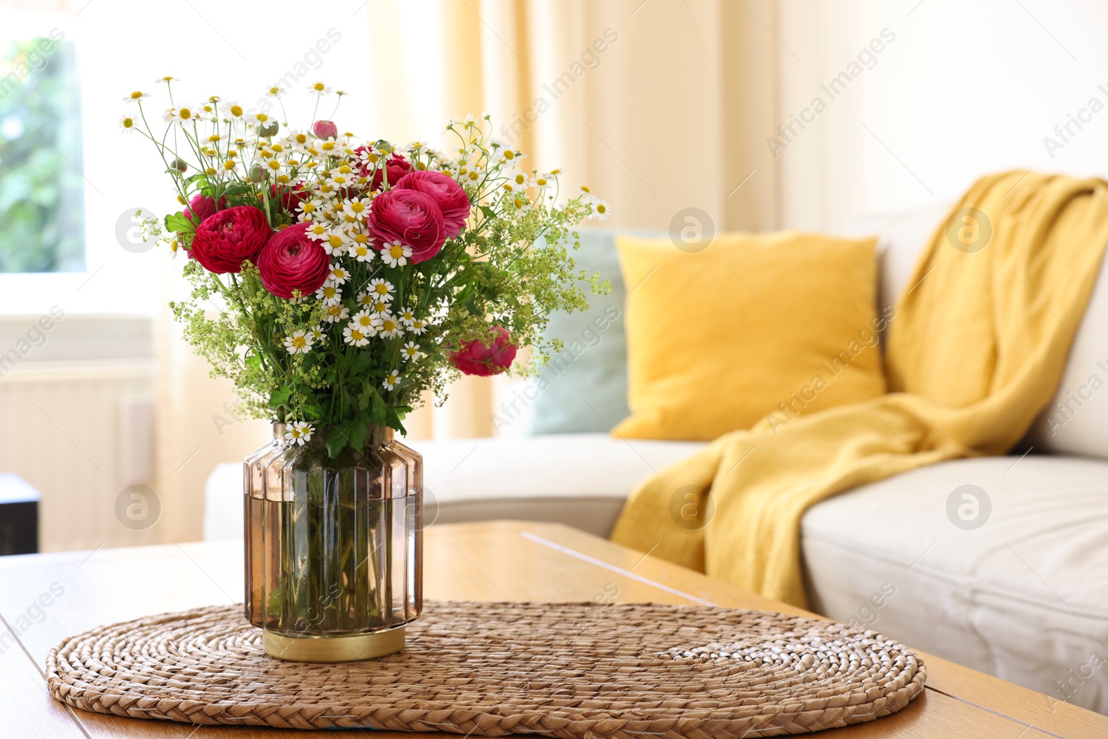 Photo of Beautiful ranunculus flowers and chamomiles in vase on table indoors