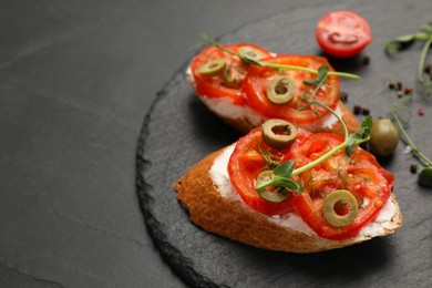 Photo of Delicious ricotta bruschettas with sliced tomatoes, olives and greens on black table, closeup. Space for text