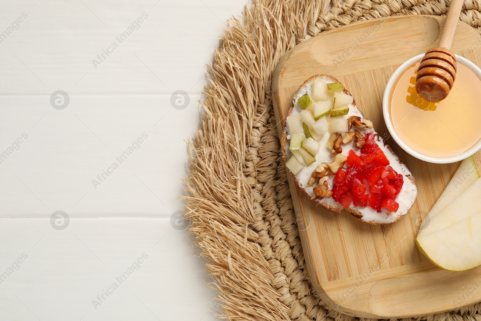 Photo of Delicious ricotta bruschetta with pear, strawberry and on white wooden table, top view. Space for text