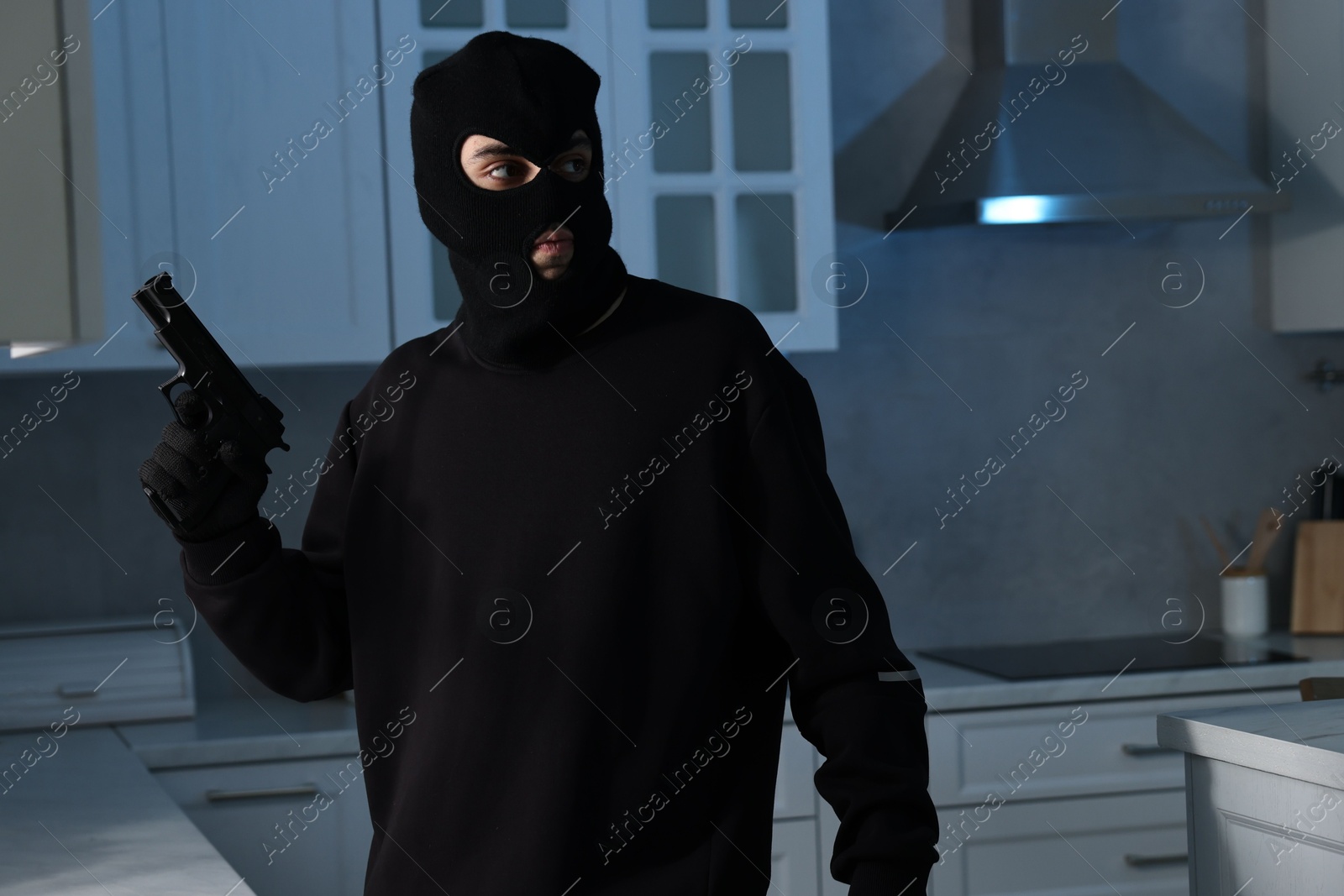 Photo of Thief wearing balaclava with gun in foreign house. Burglary