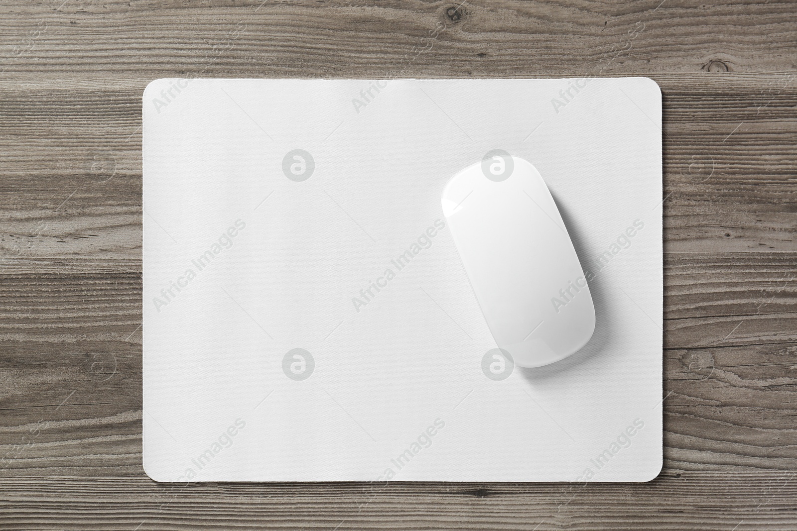 Photo of Wireless mouse and mousepad on wooden table, top view