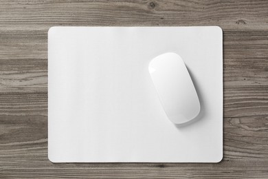 Photo of Wireless mouse and mousepad on wooden table, top view