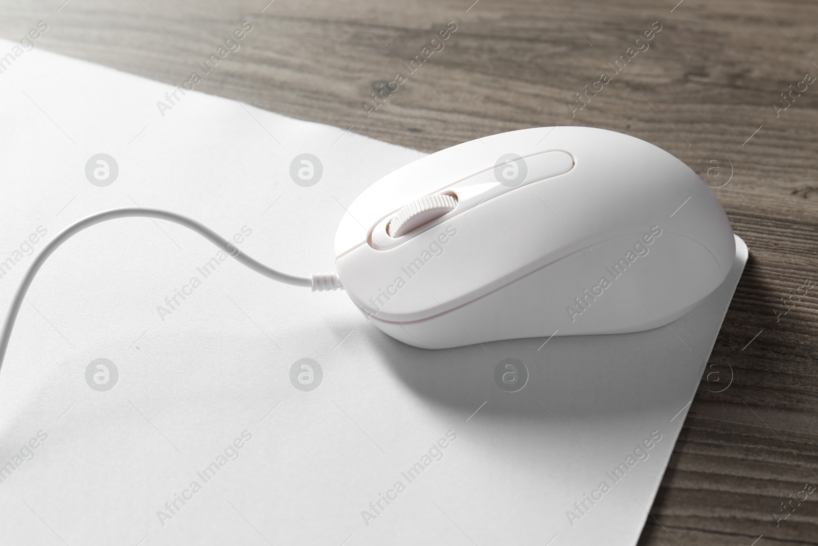 Photo of Wired mouse and mousepad on wooden table