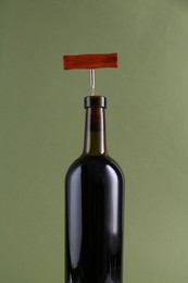 Wine bottle with corkscrew on olive background