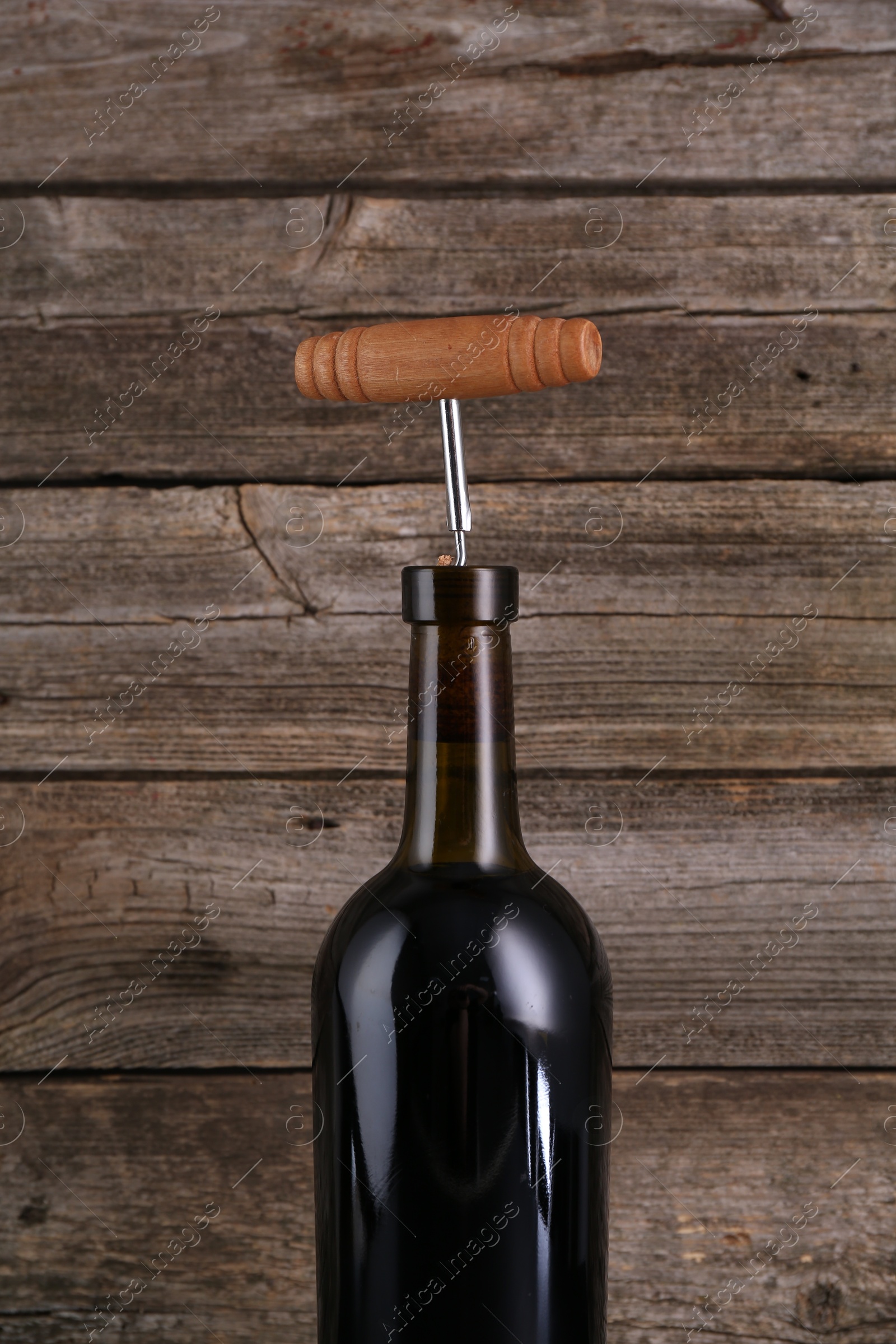 Photo of Wine bottle with corkscrew on wooden background