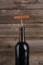 Photo of Wine bottle with corkscrew on wooden background