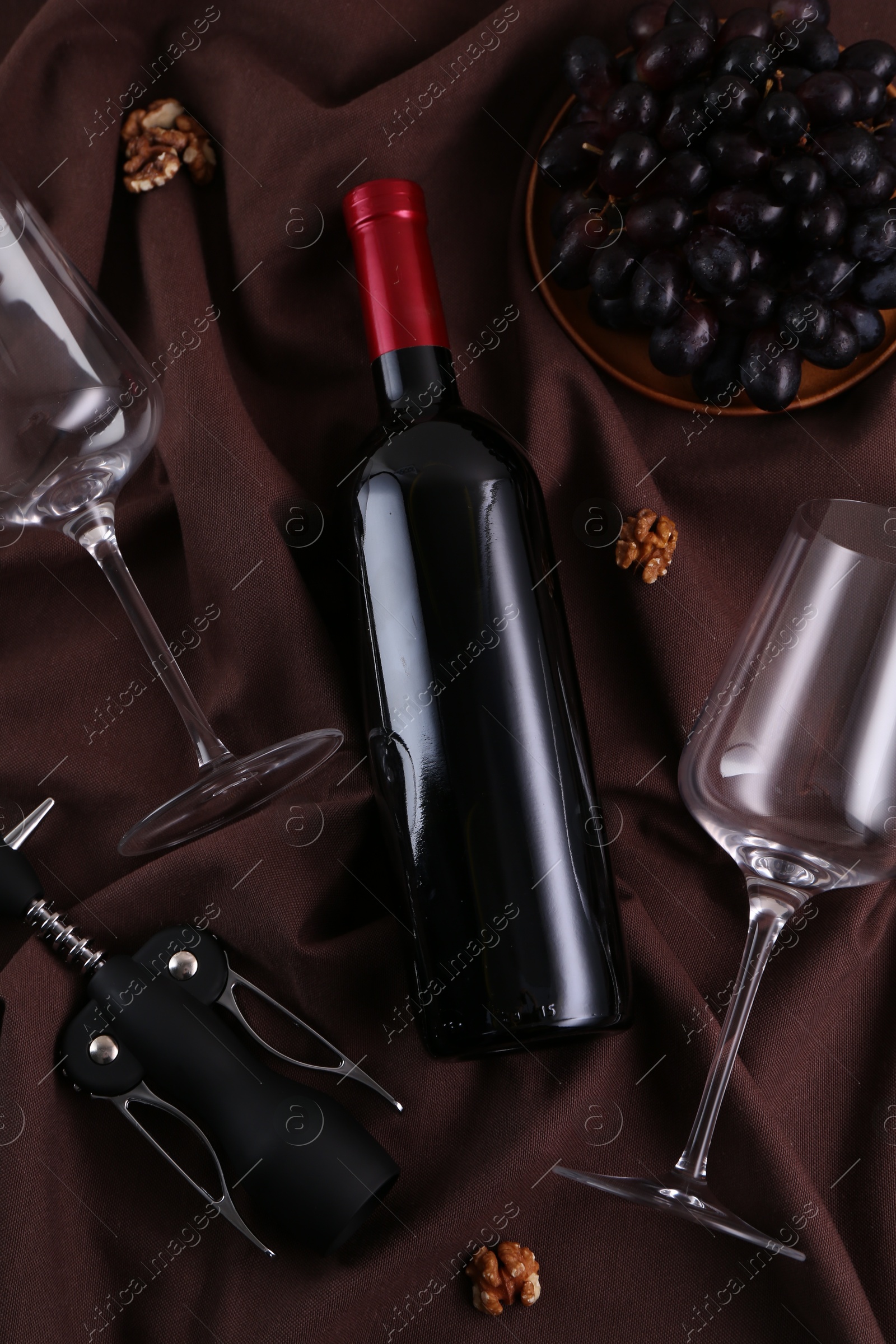 Photo of Flat lay composition with wing corkscrew and wine on brown fabric