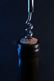 Wine bottle with corkscrew on dark background, closeup