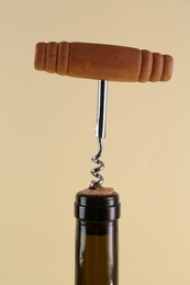 Photo of Wine bottle with corkscrew on beige background, closeup