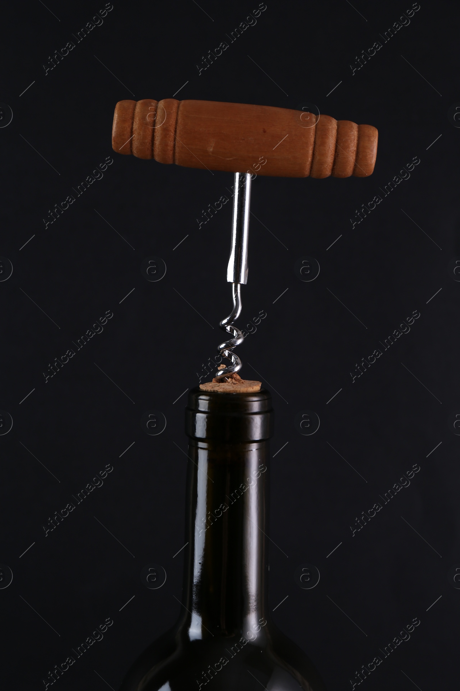 Photo of Wine bottle with corkscrew on black background