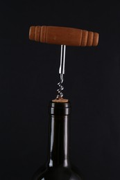 Photo of Wine bottle with corkscrew on black background